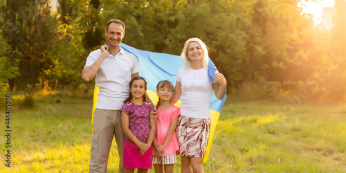 Happy family s with flag of Ukraine in field.