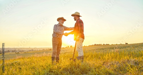 Handshake between the farmers at the field during the examining harvest. Two businessman farmer shake hands. Agree successful deal or hello. Background of agricultural field with growing ripening corn