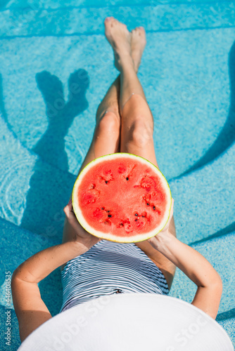Top view of woman holding watermelon in blurred swimming pool