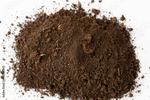 A heap of black brown peat, a natural fertilizer with particles of dead bog plants on a white background. Peat as a mineral material in natural production close-up top view