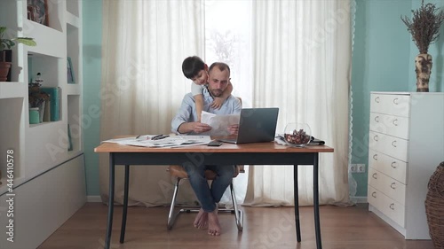 Parent working from home. SLOW MOTION Remote work. Family on self-isolation. Home office. A man is working at a table. The son interferes with the father's work. Dad gets annoyed. Quarantine. Epidemic
