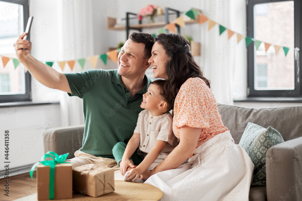 family, holidays and people concept - portrait of happy mother, father and little son with gifts and smartphone taking selfie on birthday at home party family, holidays and people concept - portrait of happy mother, father and little son with gifts and smartphone taking selfie on birthday at home party