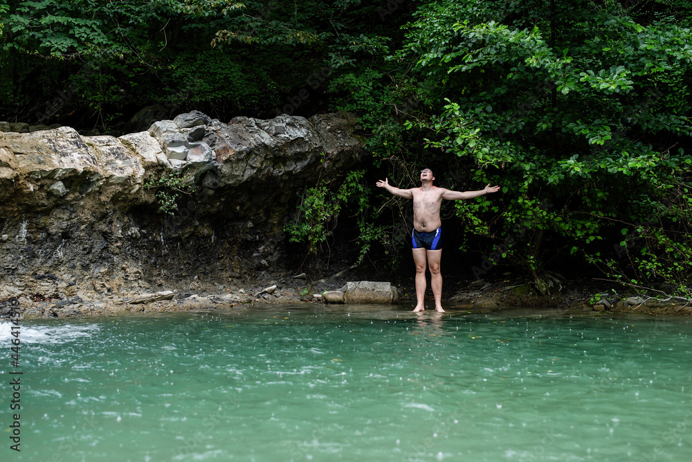 Man swimming in the mountain river with a waterfall Man swimming in the mountain river with a waterfall