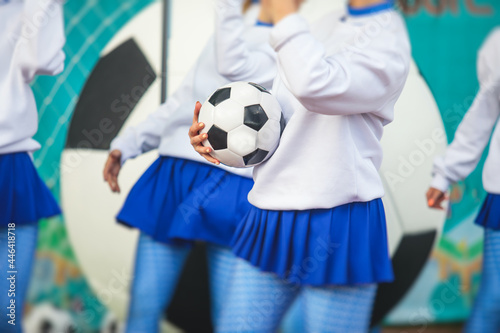 Female group of cheerleader in action, wearing white blue uniform with audience in the background performing and supporting during football game match © tsuguliev