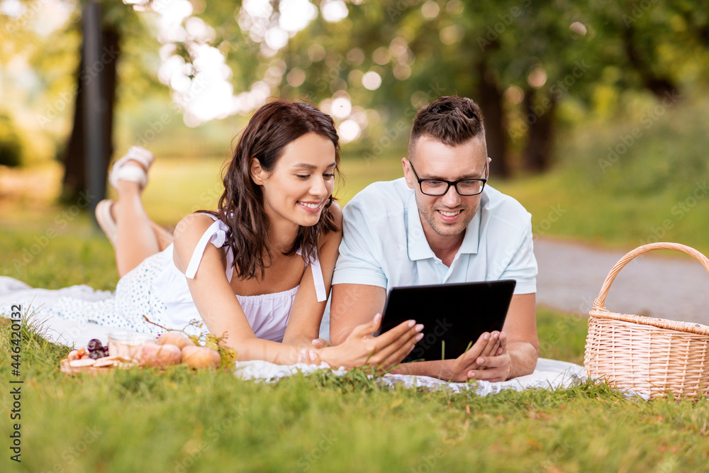 leisure and people concept - happy couple with tablet pc computer having picnic at summer park leisure and people concept - happy couple with tablet pc computer having picnic at summer park