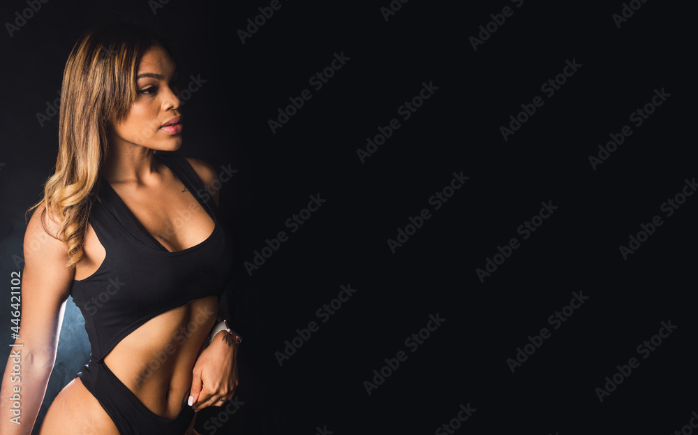 Fototapeta premium Portrait of a young Latina sportswoman on a black background.