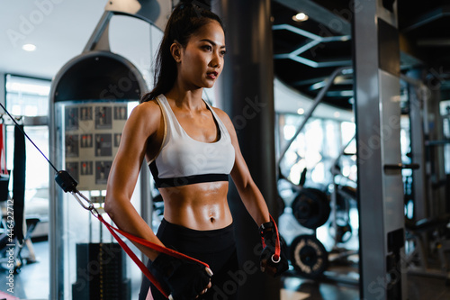 Young Asia lady exercise doing exercise-machine Cable Crossover fat burning workout in fitness class. Athlete with six pack, Sportswoman recreational activity, functional training, healthy lifestyle. photo