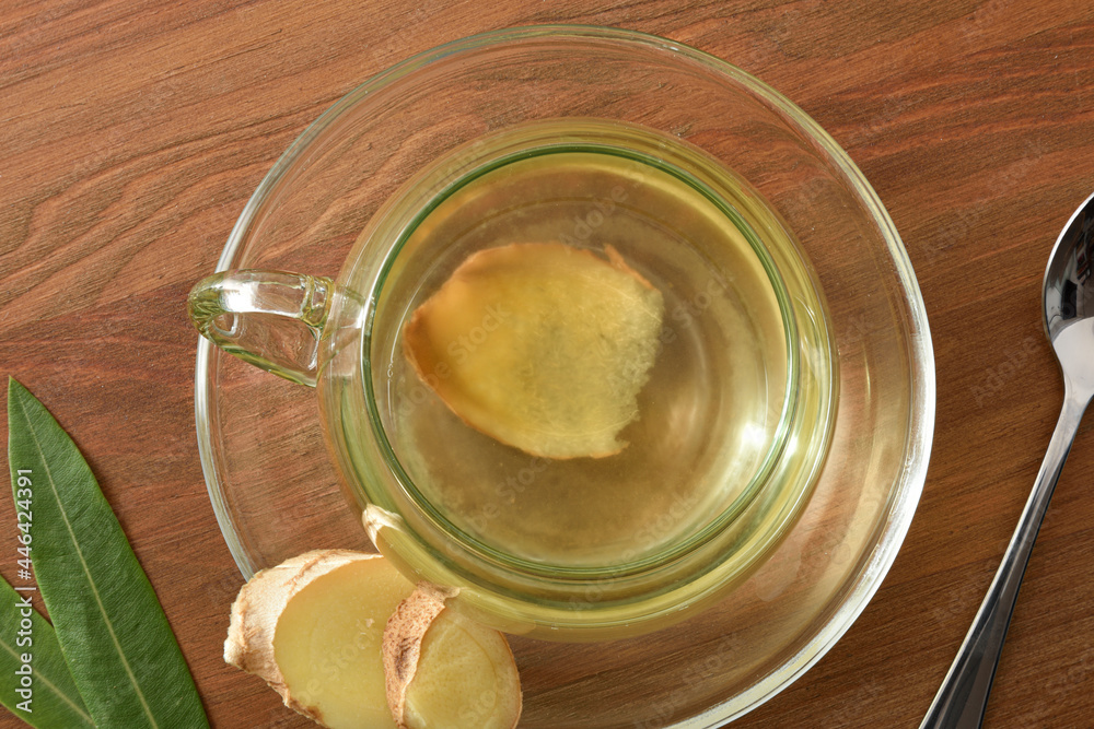 Detail of cup with ginger infusion on wooden table top Detail of cup with ginger infusion on wooden table top