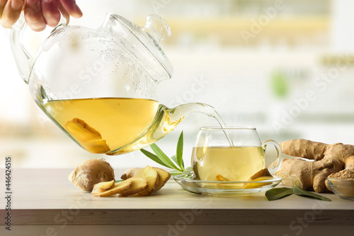 Man serving cup with ginger root infusion on kitchen bench photo