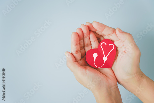 red heart paper shape with white stethoscope on hand, healthy, heart checking, health insurance concept, world health day, world hypertension day