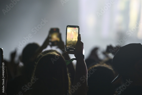 Silhouette of a unrecognizable woman holding an smartphone in a concert
