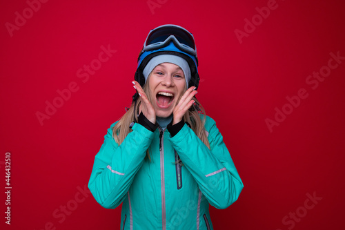 Portrait of a smiling young woman in a jacket, helmet and ski goggles