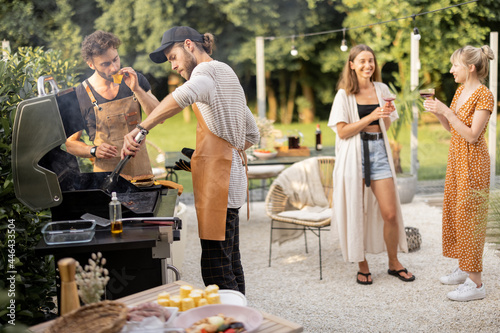 Photos Happy young friends hanging out together, grilling food on a modern grill at beautiful backyard of a country house