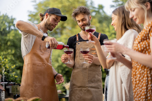 Canvas Print Young people with alcohol drinks at picnic, pouring wine or liqueur into a glasses