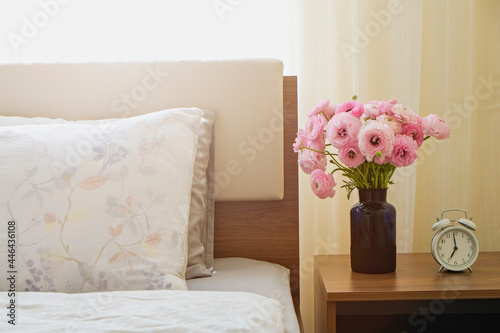 Good morning concept. Empty unmade bed with ranunculus flowers. Close up shot of beautiful spring bouquet in bedroom interior. Copy space, background. © Evrymmnt