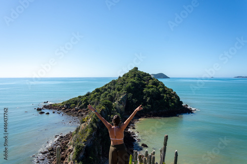 Young woman looking at Ponta do Pai Vitorio during a sunny day in Rasa Beach, Armacao dos Buzios, Rio de Janeiro, Brazil.