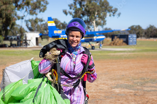 female skydiver hauling parachute back to clubhouse after a successful jump photo