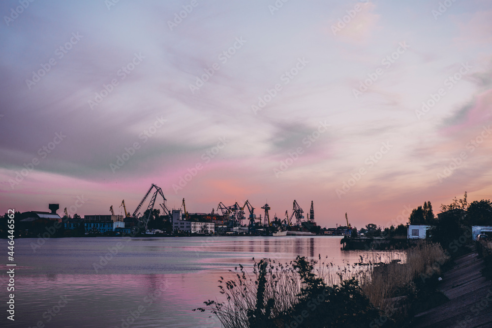 Naklejka premium ship cranes in the port at sunset