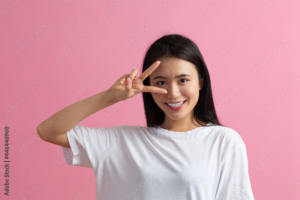 Portrait of asian positive smiling woman with V fingers gesture on pink background. Portrait of asian positive smiling woman with V fingers gesture on pink background.