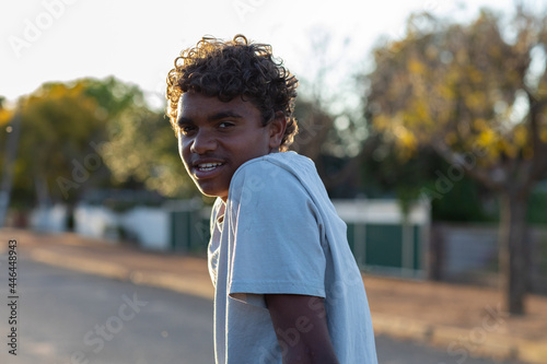 young curly-headed guy in grey tee upper body back-lit