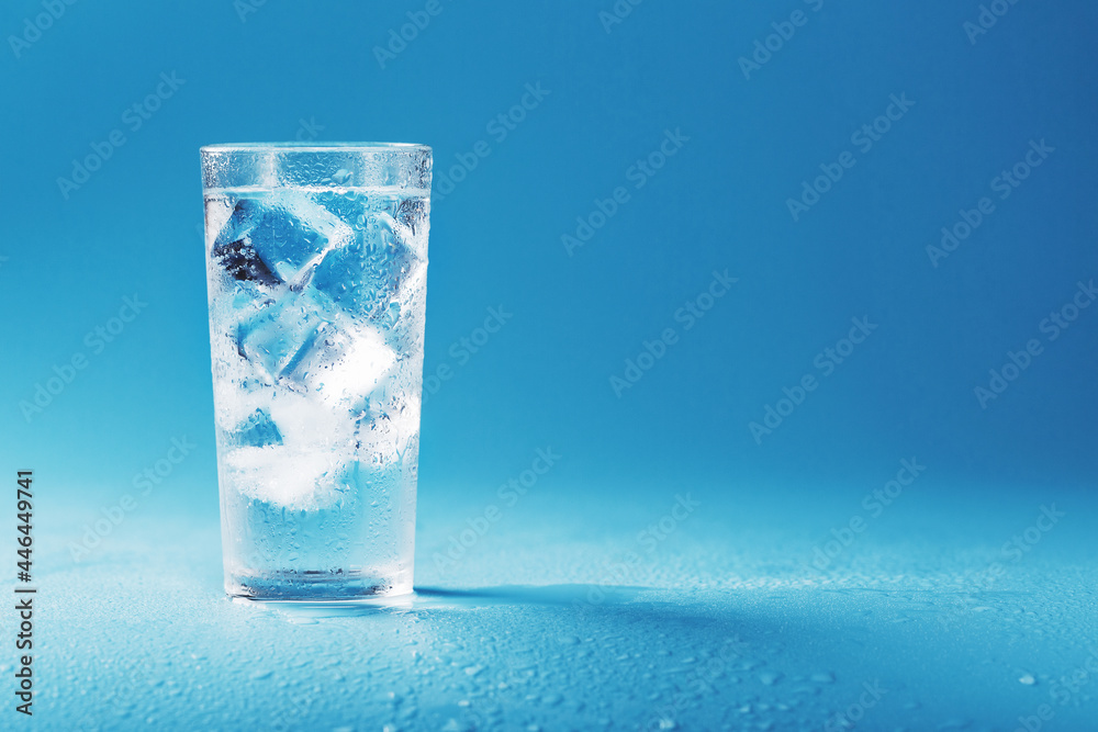 Glass with water and ice cubes on a blue background Glass with water and ice cubes on a blue background