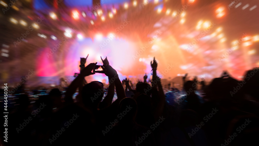 The crowd at a concert. Fun, hands up, and capture a moment by smartphones. Zoom in and out technique for powerful image