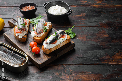 Sardines sandwich with smoked fish, on old dark wooden table background, with copy space for text