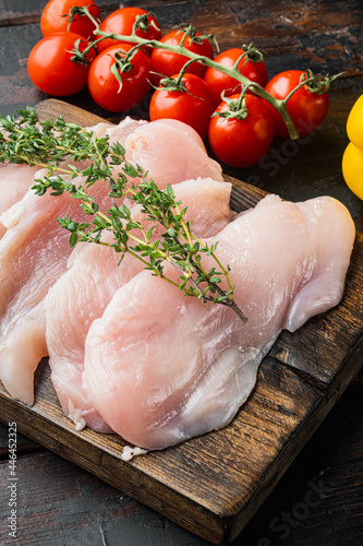 Slices of raw chicken meat fillet, on old dark wooden table background