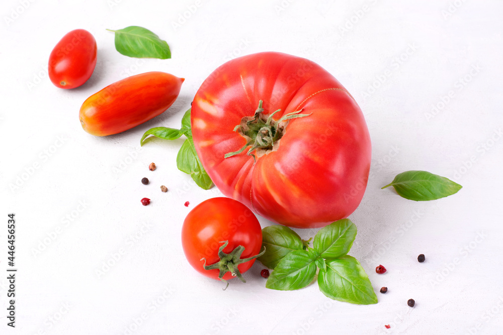 Tomatoes variety, basil and pepper on the white table. Harvest of organic vegetable. Ingredients for a salad Tomatoes variety, basil and pepper on the white table. Harvest of organic vegetable. Ingredients for a salad