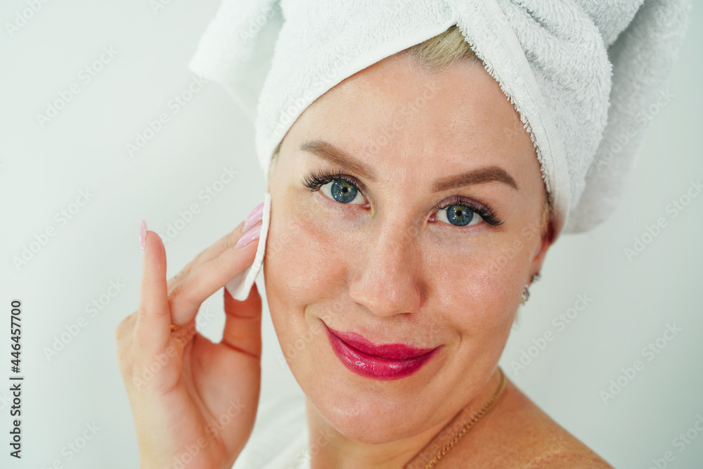 Close up beauty portrait of young attractive smiling woman cleansing face with cotton pad Close up beauty portrait of young attractive smiling woman cleansing face with cotton pad