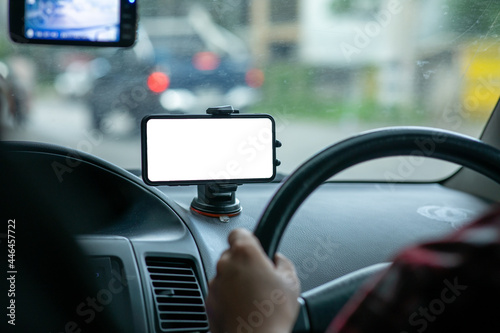 Driver's hand on the steering using mobile phone while driving car at sunset, road trip travel and Driver using GPS concepts.