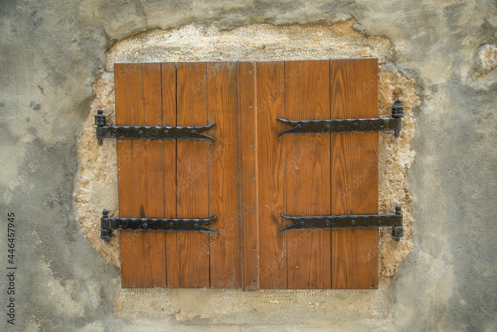Old wooden shutters with wrought iron on a stone wall ideal for a photo