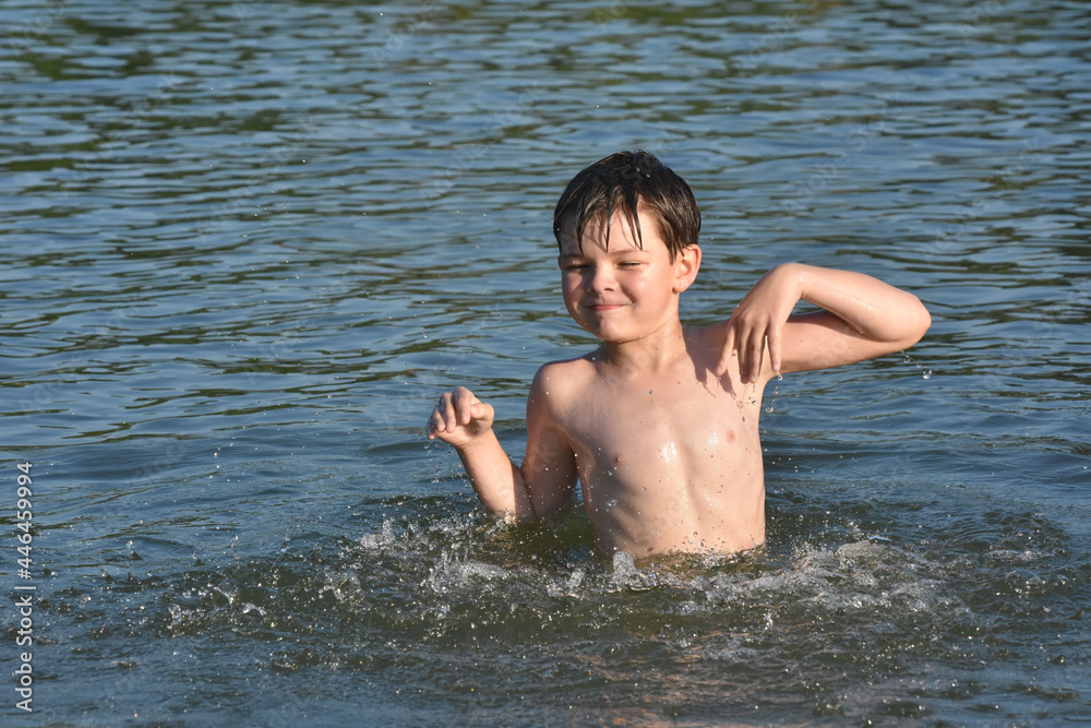 Child playing and swimming in the water. Boy splashing in a water on hot sunny day