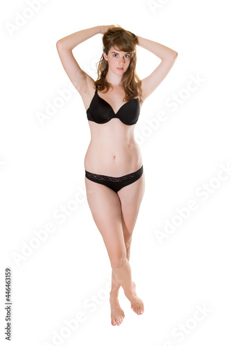 Full length portrait of an attractive brunette woman wearing black underwear, isolated in front of white studio background