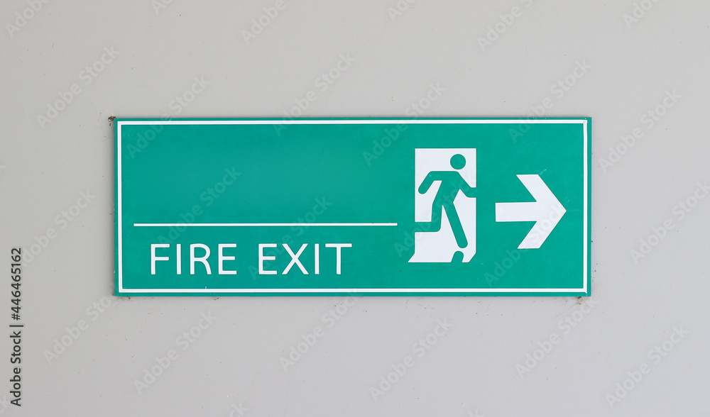 Attention green Exit sign with arrow on white background wall.