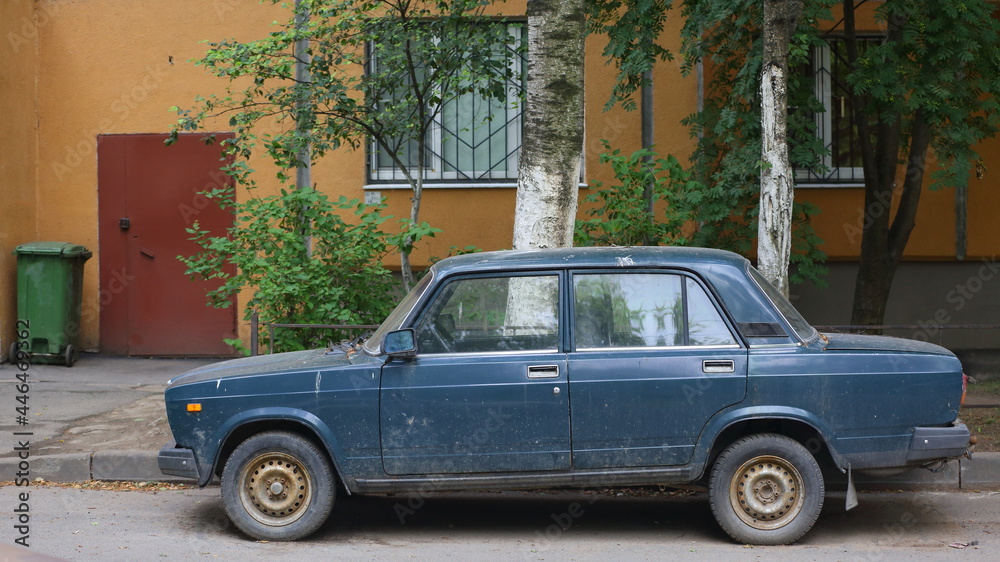 An old blue Soviet car in the courtyard of a residential building, Dybenko Street, St. Petersburg, Russia, July 2021