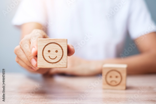 Man hand holding emotion face block. Customer choose Emoticon for user reviews. Service rating, ranking, customer review, satisfaction, evaluation and feedback concept