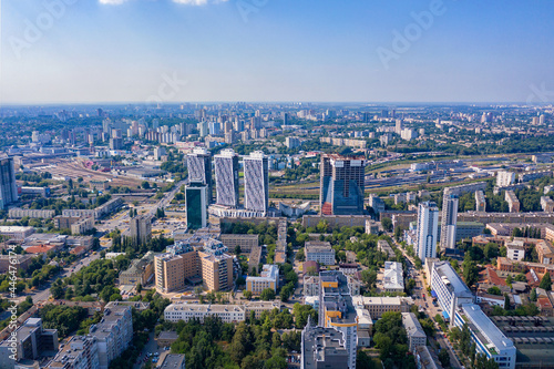 Aerial photography, sunlight illuminates urban residential areas and green parks in the summer blue haze. © Sergii