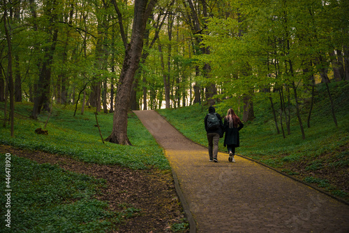 two people back to camera walking on pawement road in park weekend rest spending time © Артём Князь