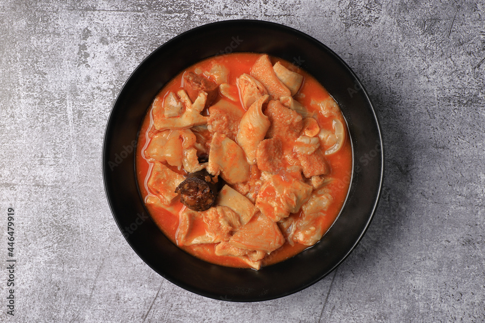 Ration of Madrid-style tripe on a black plate on a gray table Ration of Madrid-style tripe on a black plate on a gray table