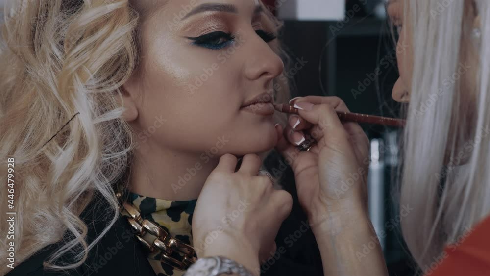 The make-up artist uses a light brown pencil to contour the woman's lips. The process of applying makeup at home by a professional. Beauty industry. Artistic concept The make-up artist uses a light brown pencil to contour the woman's lips. The process of applying makeup at home by a professional. Beauty industry. Artistic concept