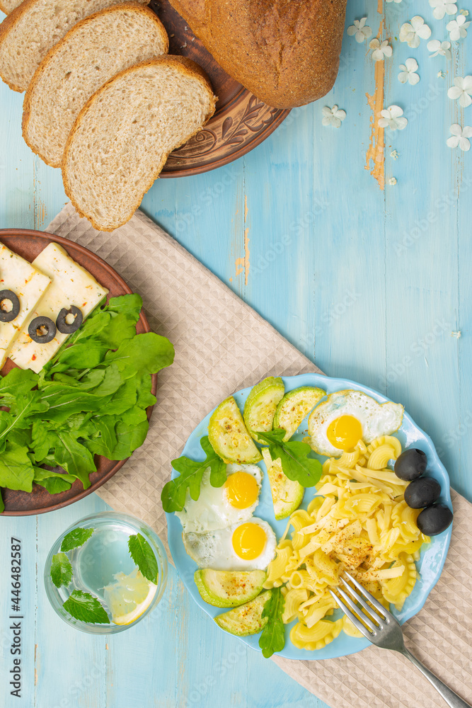 Durum pasta, eggs, greens, arugula, proper nutrition, top view on a wooden blue background

