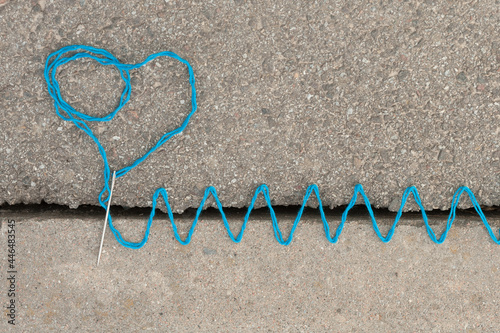 the crack in the asphalt is sewn with colorful threads symbolizing the union of incompatible or illogical things