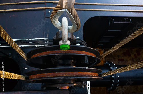 Stretched steel cables, shackle and rollers of a cargo crane, close-up.