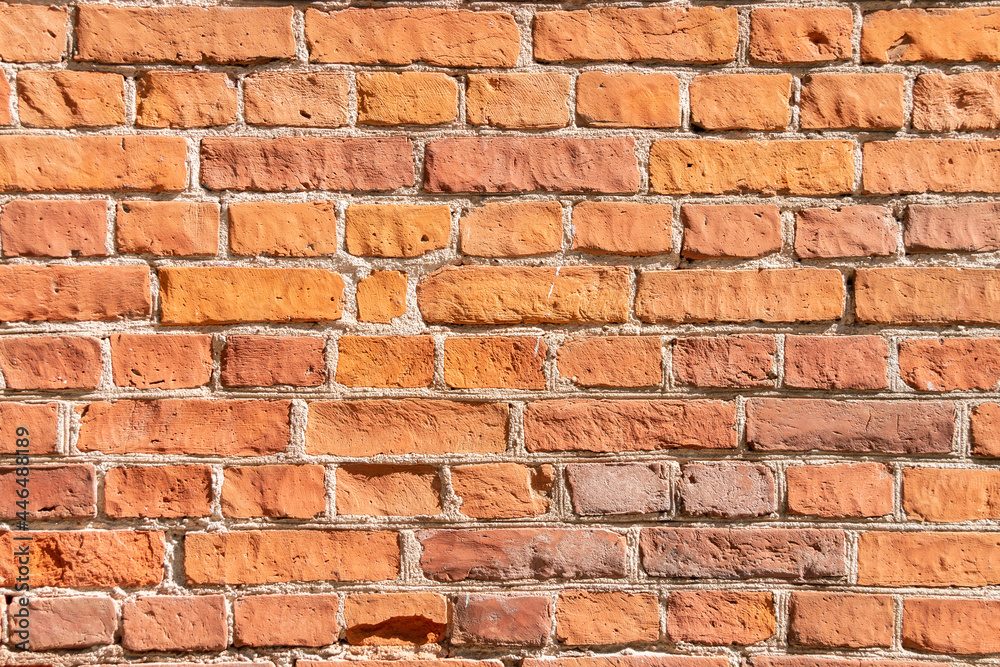 Fototapeta premium Old brown brick wall. Grunge background with red bricks and layers of cement.