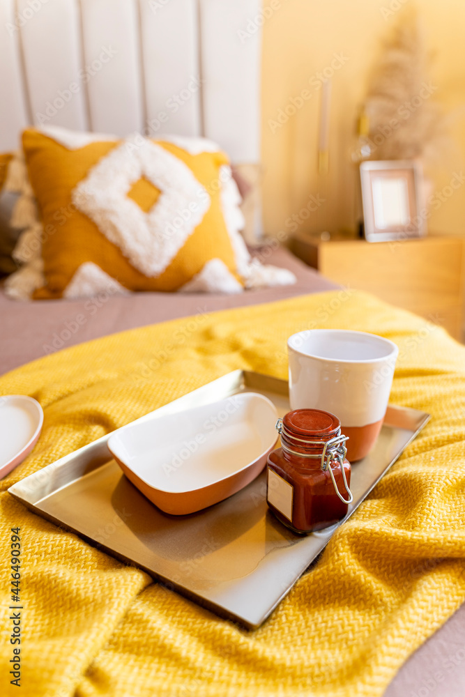 Bedroom breakfast, home accents, tray food whit empty coffee mug and marmalade jar in bed yellow blanket angle view