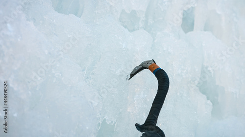 Photography Point of view ice climber swinging the ice axe into the vertical ice covered sur