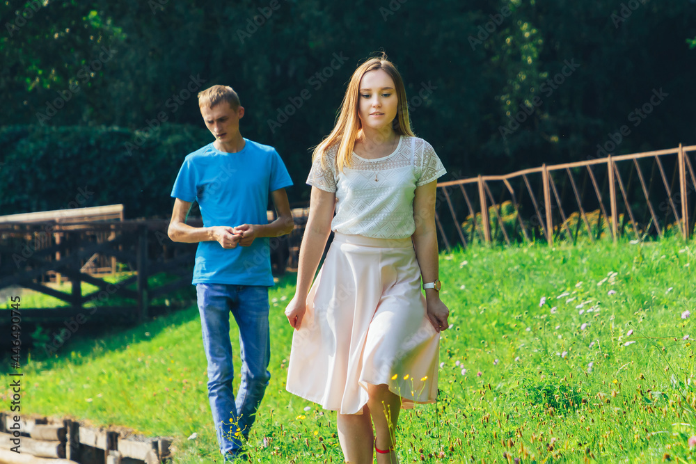 Fototapeta premium A couple in love walks in a summer park by the lake.A woman leaves her man