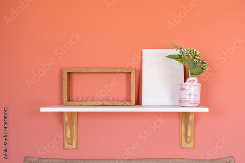 Home accents, empty canvas, poster, blank frame mock up, on a red wall, bed room, wooden decor front view
