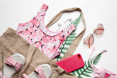 Fashion girl clothing and accessories on white background with green leaves. Summer beach concept. Flat lay, top view. 